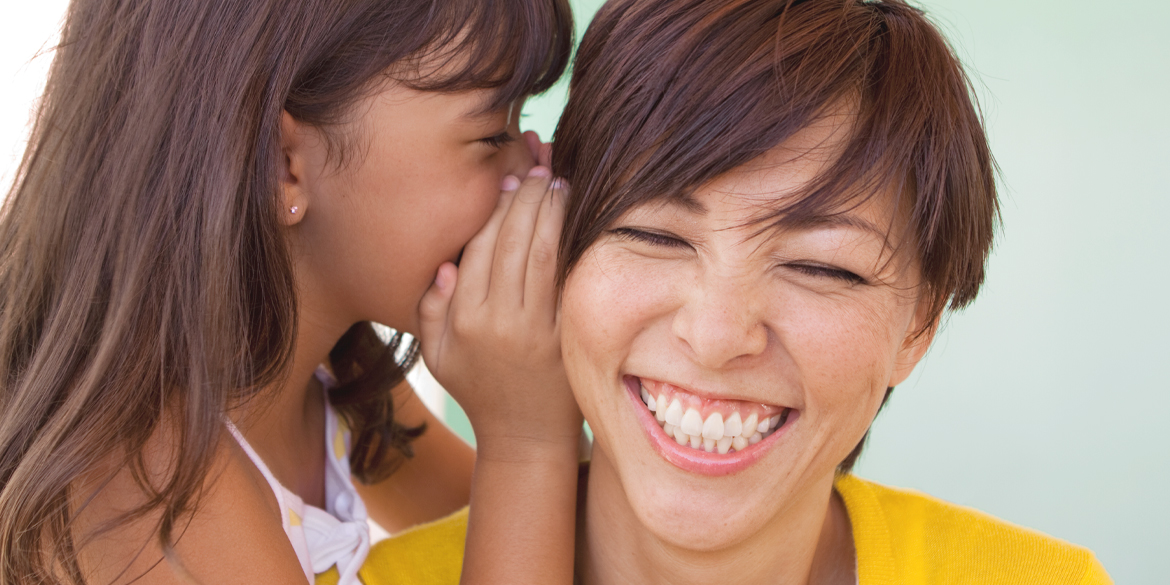 A woman in her 40's laughing with her child beside her