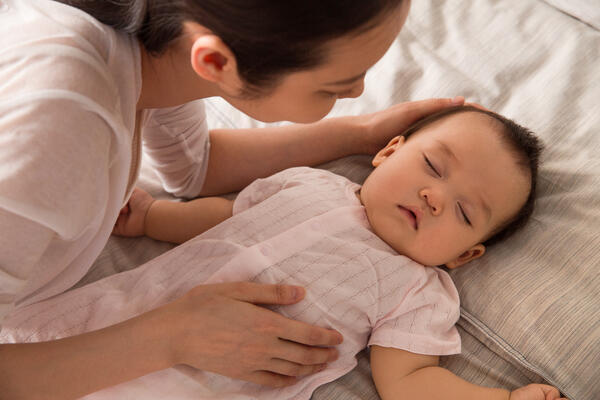 Baby feeling sick, sleeping in bed